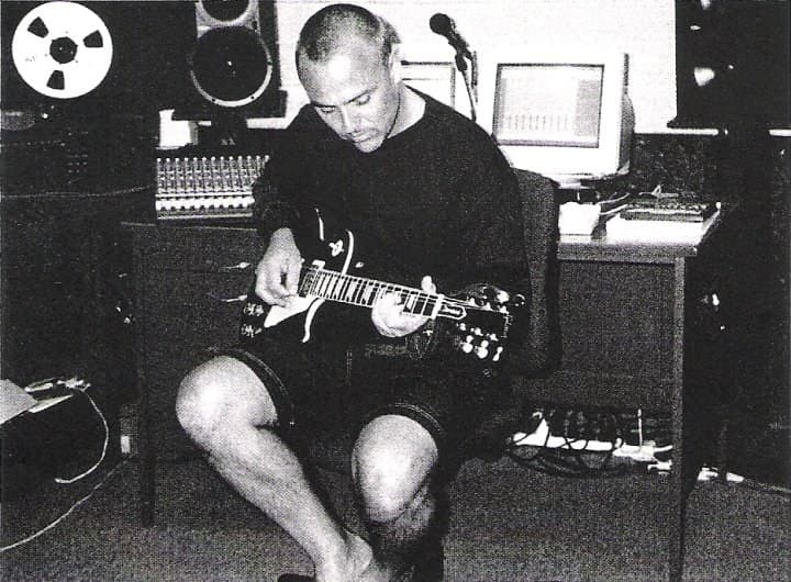 Rikki playing guitar in the studio, black and white